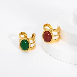 Detailed shot of two vintage gold-plated rings with green and red oval stones and hammered texture
