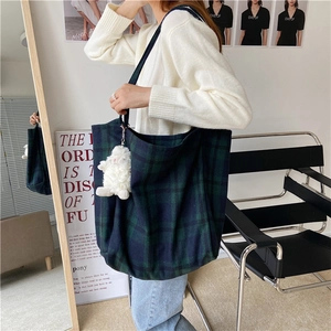 Deep green plaid tote bag with lamb wool sheep pendant shown in a lifestyle indoor setting