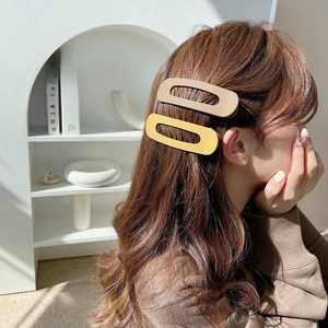 Side view of woman wearing beige and yellow matte oval hair clips in natural sunlight