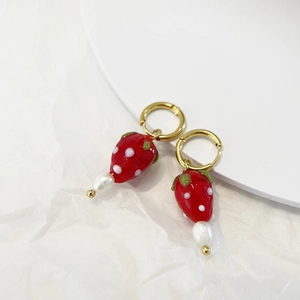 Close-up of strawberry earrings with red glass, fresh pearls and gold ear hoops
