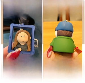Detail of cartoon Mona Lisa and Van Gogh keychain pendants in blue relief frames