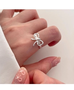 Close-up of a s925 silver bow-shaped open ring worn on a model's finger with soft lighting