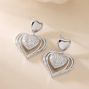 Luxury copper-plated gold heart earrings with sparkling cubic zirconia on beige paper