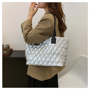 Silver metallic tote bag with quilted stitching shown on model in modern interior