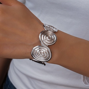 Close-up of wide silver metal cuff bracelet with a unique spiral vortex geometric design