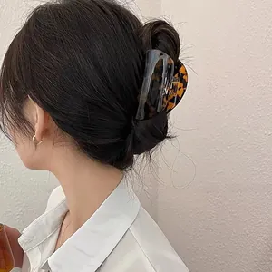 Large amber acetate hair claw clip shown in a stylish French twist hairstyle on model