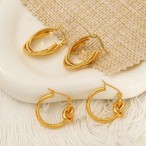 Elegant 18K gold layered hoop and love knot earrings displayed on white ceramic tray