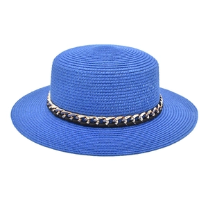 Détail d'un chapeau de paille bleu roi à calotte plate avec une chaîne dorée chic