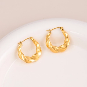 French style 18k gold plated twisted hoop earrings on a minimalist white ceramic plate