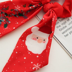 Detailed close-up of red Christmas scrunchie with Santa Claus and snowflake patterns