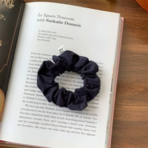 Detail view of dark blue fabric scrunchie with From Sheep label on an open book