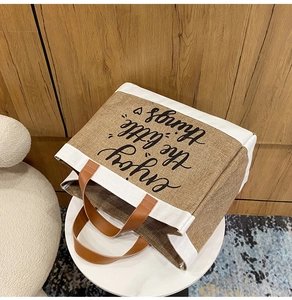 Dettaglio borsa tote in lino con scritta stampata e manici in pelle marrone scuro