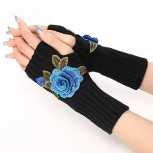 Close-up of black knitted fingerless gloves with blue rose embroidery on model hands