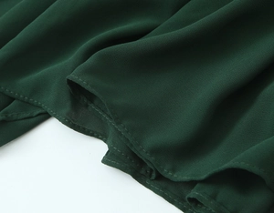 Macro detail of dark green chiffon fabric with fine stitching and soft pleated texture