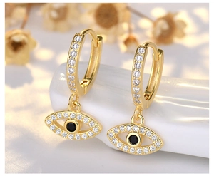 Macro detail of gold evil eye earring charm with sparkling zircon stones and black gem