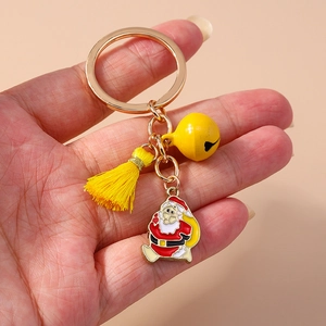 Macro shot of Santa Claus keychain with yellow tassel and bell held in hand