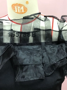 Detail der mehrlagigen schwarzen Netzvolants und des transparenten Ausschnitts am Kleid