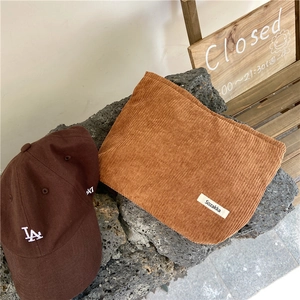 Close-up of warm brown corduroy makeup bag with detailed vertical ribbing and fabric logo tag
