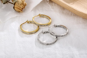 Close-up of gold and silver hoop earrings featuring white rhinestones in a refined setting