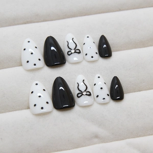 White polka dots and black bow design on elegant almond-shaped press-on nails