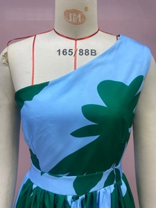 Close-up of light blue one-shoulder maxi dress featuring large green leaf print details