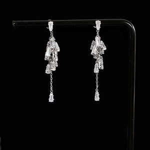 Elegant silver tassel earrings with sparkling zircon crystals on a black display stand