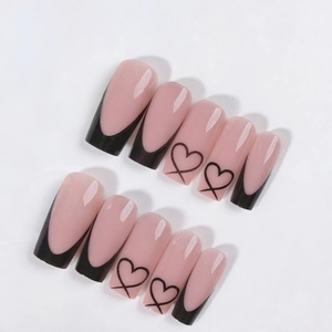 Pink press-on nails with black French tips and heart patterns in a long coffin shape