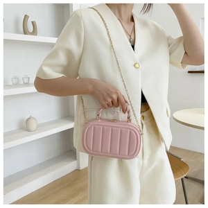 Detailed view of pink quilted box bag with gold chain strap and woven top handle