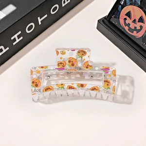 Detail of a transparent Halloween hair claw clip with orange pumpkin and BOO patterns