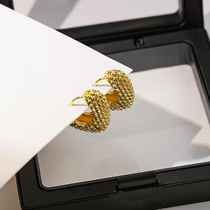 Gros plan de créoles dorées épaisses à texture torsadée dans un écrin à bijoux