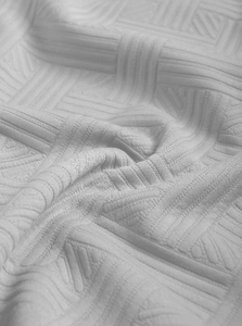 Gros plan sur un tissu jacquard blanc avec texture et motifs géométriques raffinés