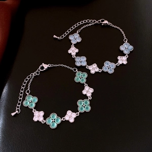 Close-up of four-leaf clover bracelets with light blue and green cat eye stones