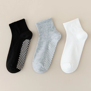 Close-up of non-slip silicone grip soles on kids' cotton mesh socks in white, grey, and black