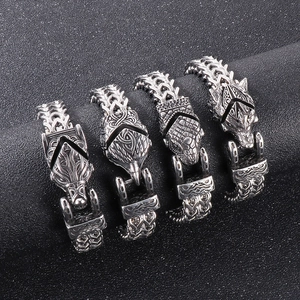 Detailed view of silver viking wolf and eagle head pendants on black textured sand