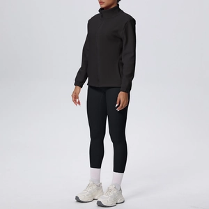 Vista laterale del set sportivo nero da donna con giacca in pile e pantaloni elasticizzati