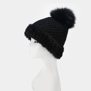 Close-up of black cable knit beanie with large faux fur pom poms and thick plush trim
