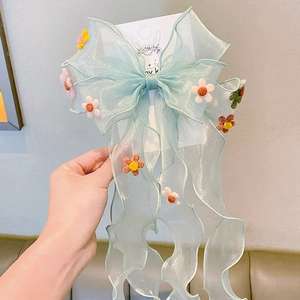 Detail of light green sheer ribbon hair clip with colorful felt flowers and long streamers