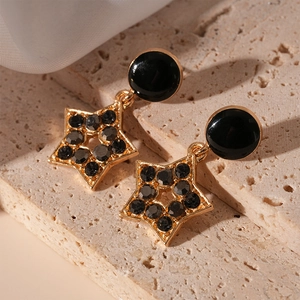 Gros plan de boucles d'oreilles étoile en strass noir sur un support en pierre beige