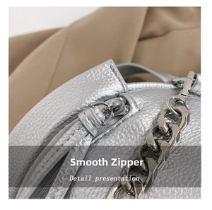 Detailed close-up of smooth silver zipper and lychee pattern leather on crossbody bag