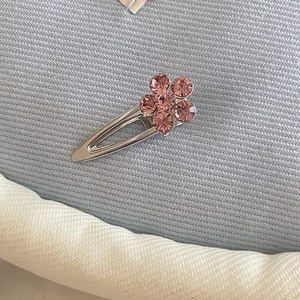 Silver metal BB clip featuring pink rhinestone flower on textured blue fabric background