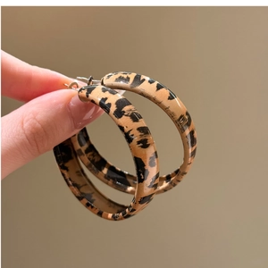 Detailed view of leopard print acrylic hoop earrings with a glossy tortoiseshell finish