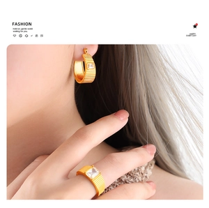 Dettaglio del set di gioielli placcati in oro con orecchini a righe e anello con zircone