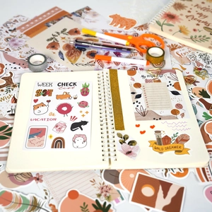 Bohemian journal kit with spiral notebook, stickers, washi tapes, and pens on a desk