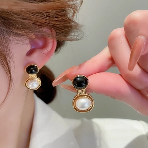Detail of vintage French style black and white pearl earrings with golden metal accents