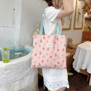 Close-up of pink quilted canvas tote bag with cute bear patterns and blue shoulder strap