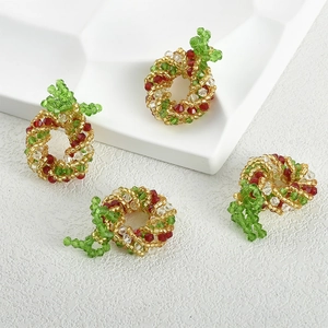 Close-up of four handmade Christmas wreath beaded charms with red bows for DIY jewelry