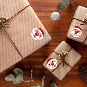 Merry Christmas Santa Claus round stickers applied to kraft gift box on wooden desk