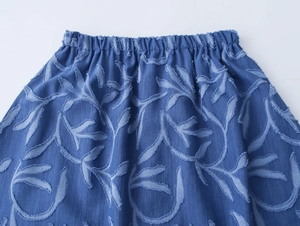 Detailed macro view of the elastic waistband on blue denim leaf pattern jacquard skirt