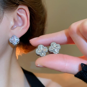 Close-up of sparkling four-leaf clover stud earrings with silver metal and zircon stones