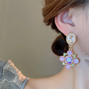 Détail de la boucle d'oreille fleurie dorée avec cristaux et pierres roses sur modèle